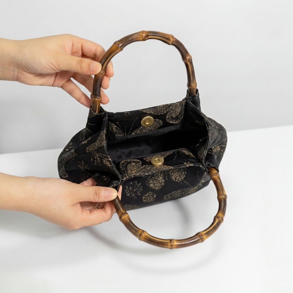 Demonstrating the interior capacity and exquisite craftsmanship of the black brocade satchel.