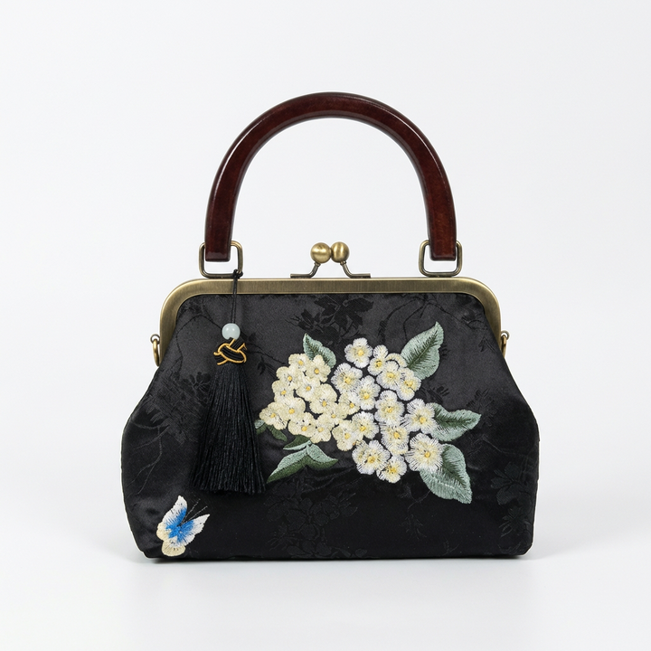 Sophisticated black silk handbag with floral embroidery and a dark vintage-style wooden handle.
