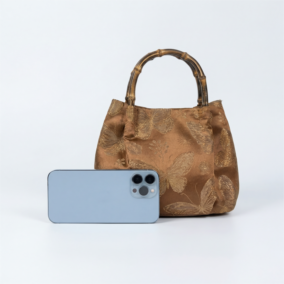 Proving the daily utility of the bronze bamboo satchel with a smartphone size comparison.