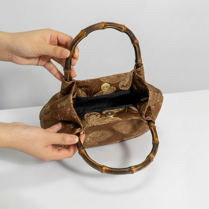 Opening the bronze bamboo handle bag by hand to show its spacious and practical interior.