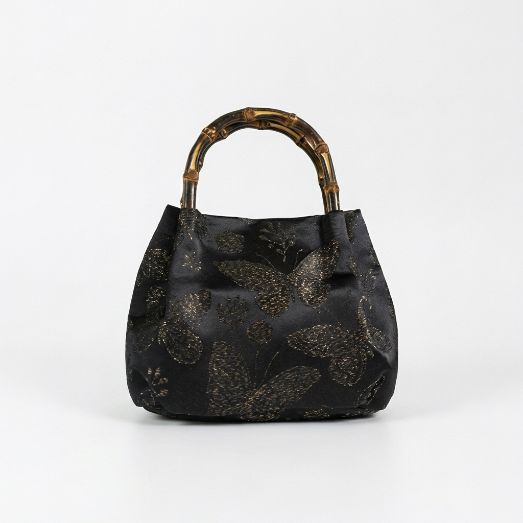 Front-facing shot of the classic black butterfly brocade satchel with a sturdy bamboo handle.