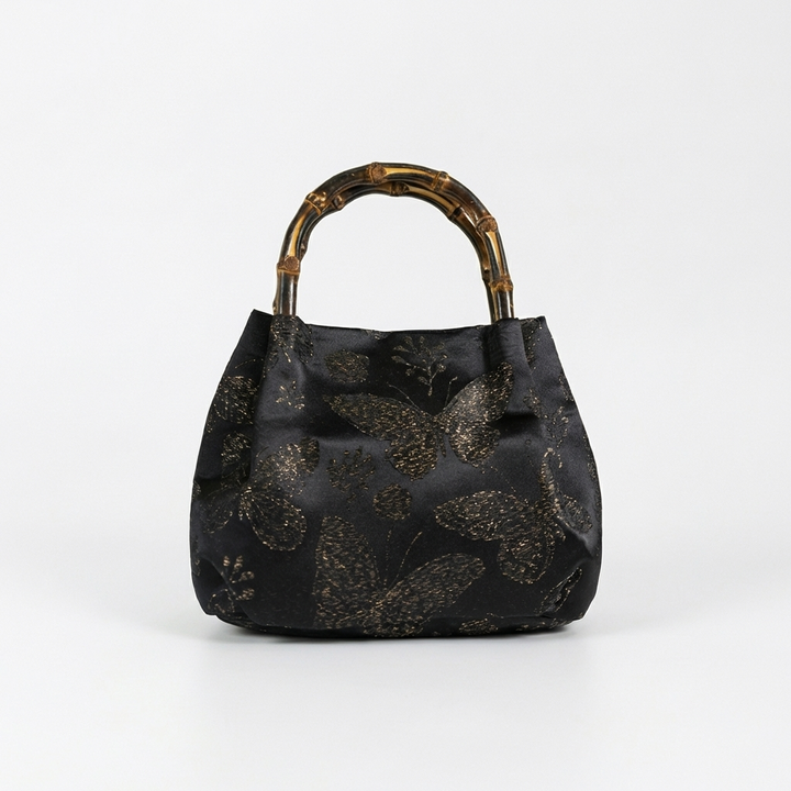 Front-facing shot of the classic black butterfly brocade satchel with a sturdy bamboo handle.