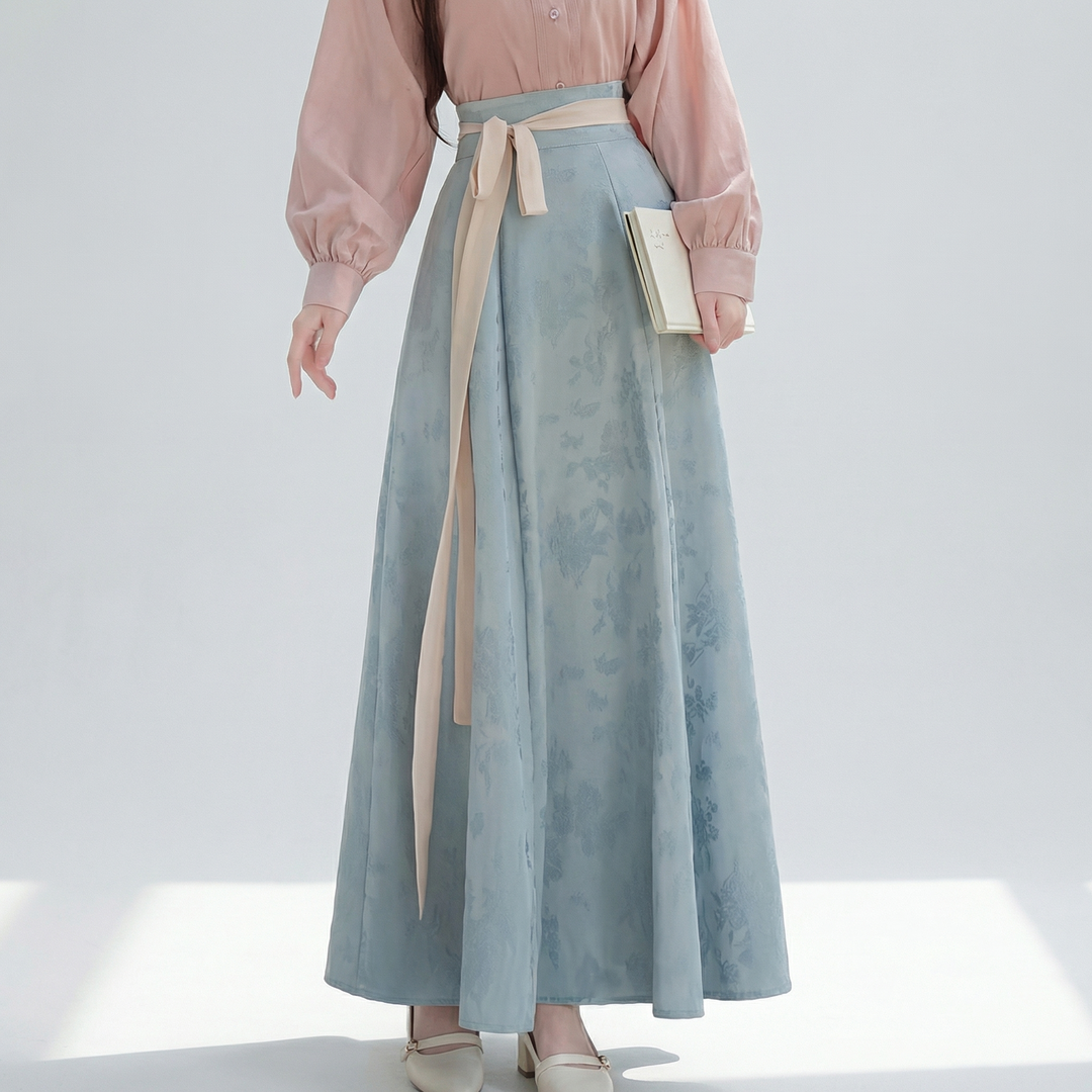 Detailed view of the dusk blue maxi skirt showing the subtle floral jacquard weaving and the elegant pastel pink waist tie.