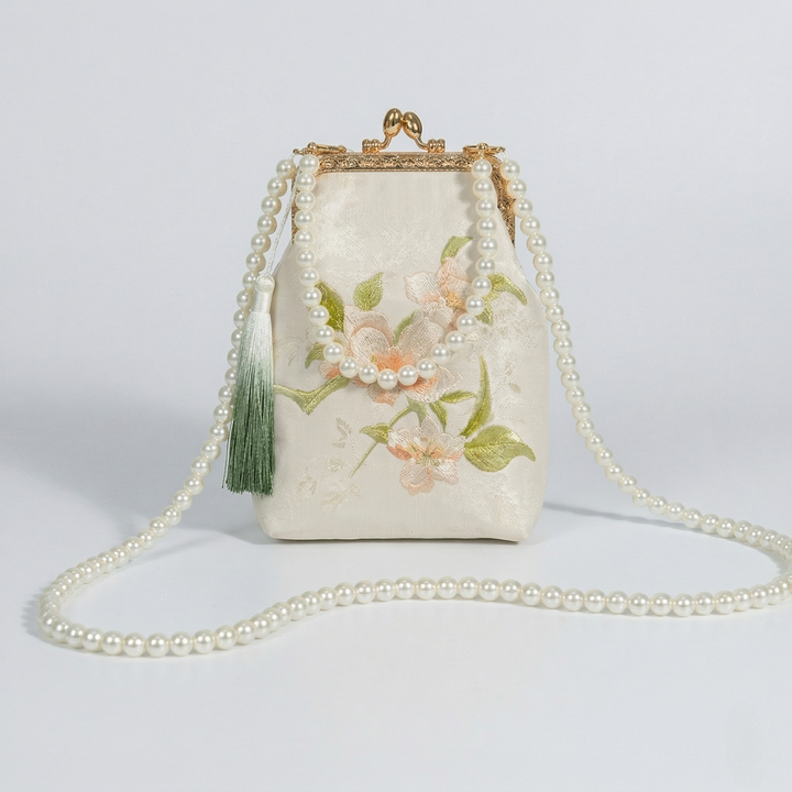 Off-white floral mini bag styled with a long pearl crossbody strap for a romantic and classic look.