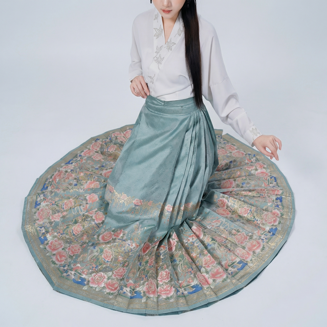 A top-down view of the pleated skirt spread out in a circle, showcasing its full volume and the beautiful artistic floral border at the hem.