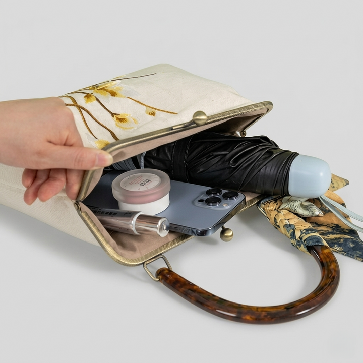 Interior view of the open embroidered doctor bag, showing its ability to hold an umbrella, makeup, and essentials.