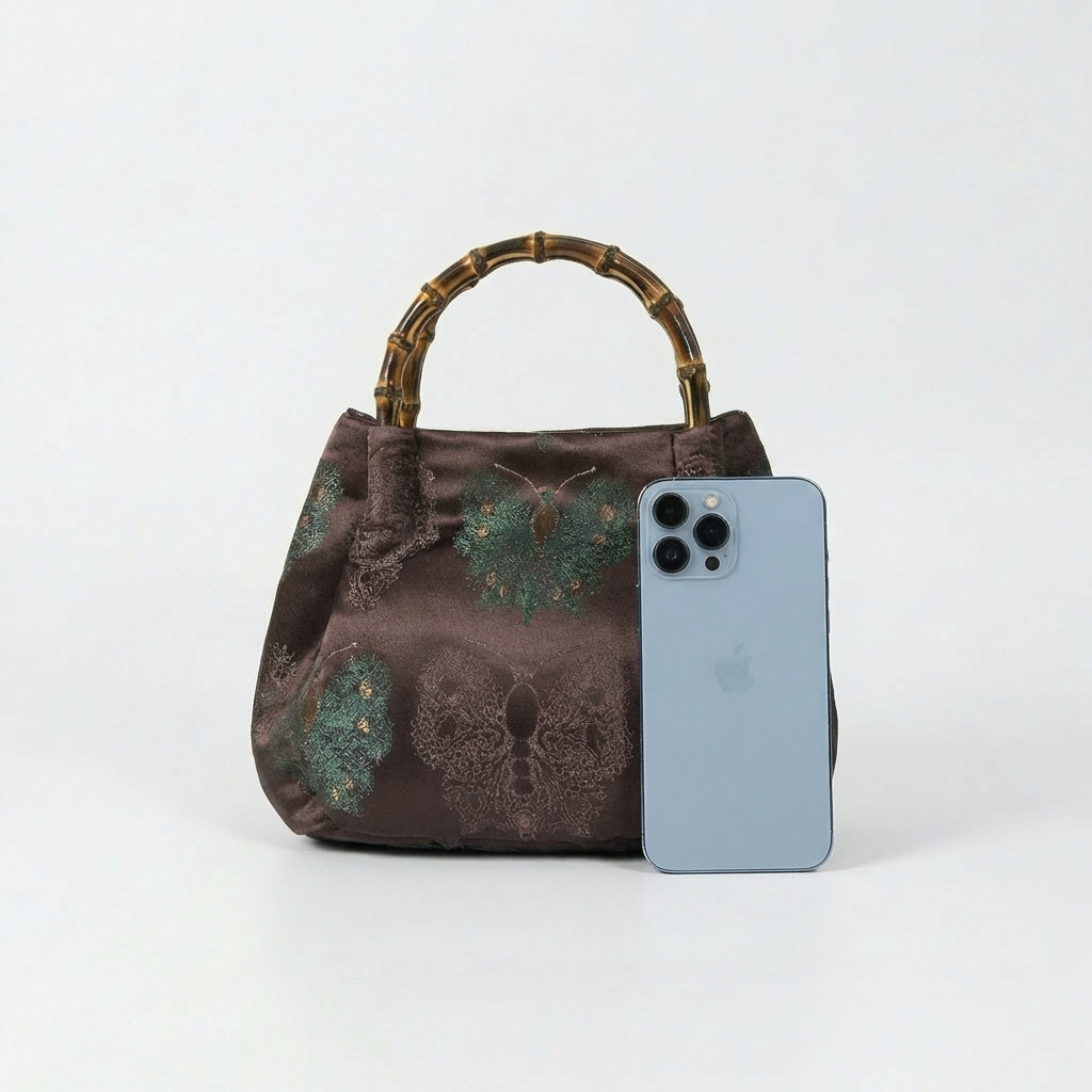 Size comparison between the maroon bamboo satchel and a smartphone to show scale and utility.