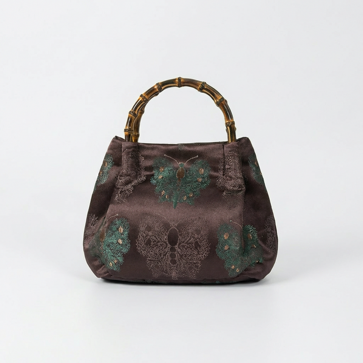 Elegant maroon brocade satchel featuring traditional patterns and a sturdy handcrafted bamboo top handle.