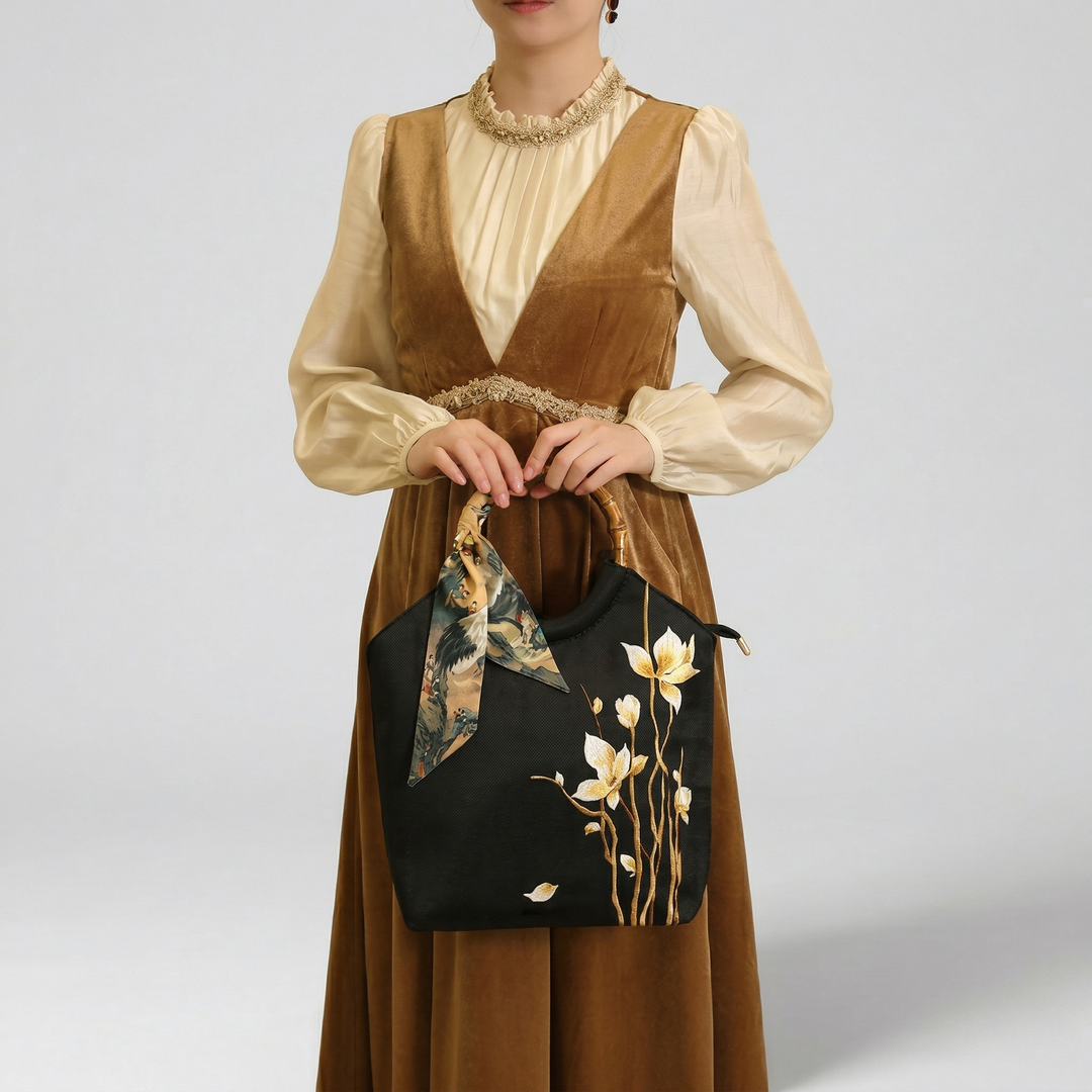 Fashion model carrying the black floral tote bag, paired with a warm brown autumnal dress for a sophisticated look.