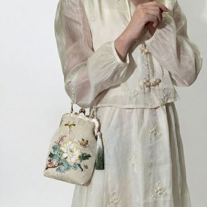 Fashion model wearing the mini floral embroidered bag as a crossbody, paired with a soft white aesthetic dress.