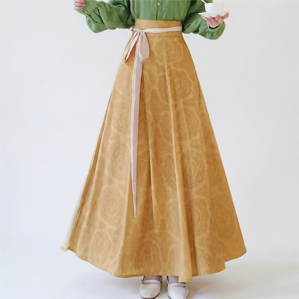 Close-up of the mustard yellow flowing skirt, highlighting the vintage-inspired pattern, paneled construction, and elegant waist tie.