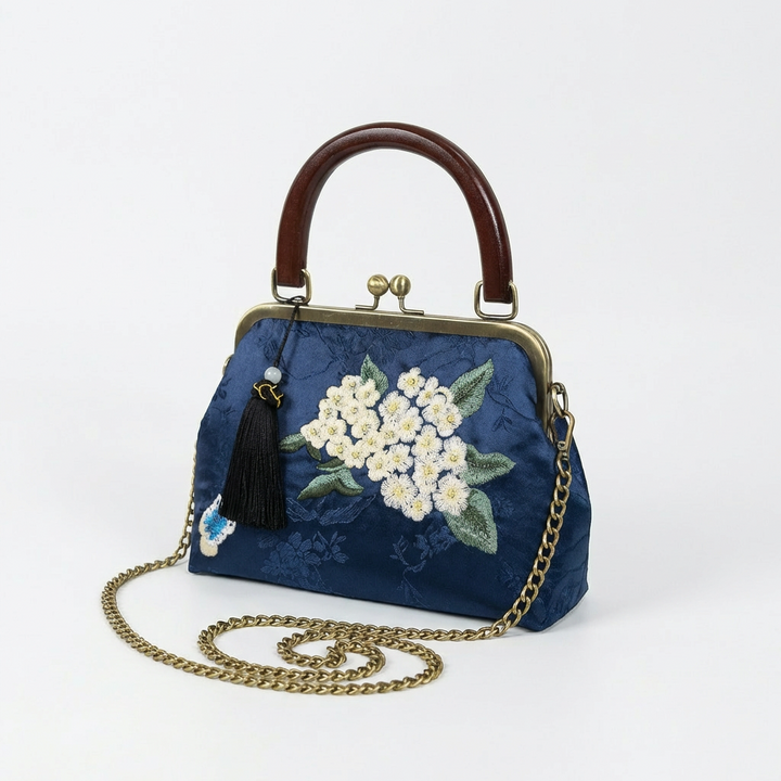 Navy blue silk embroidered bag shown with its detachable gold chain strap for crossbody or shoulder wear.