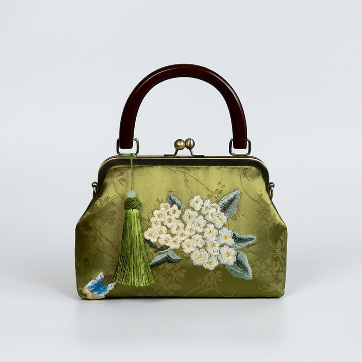 Charming olive green silk handbag with a decorative green tassel and white floral embroidery.