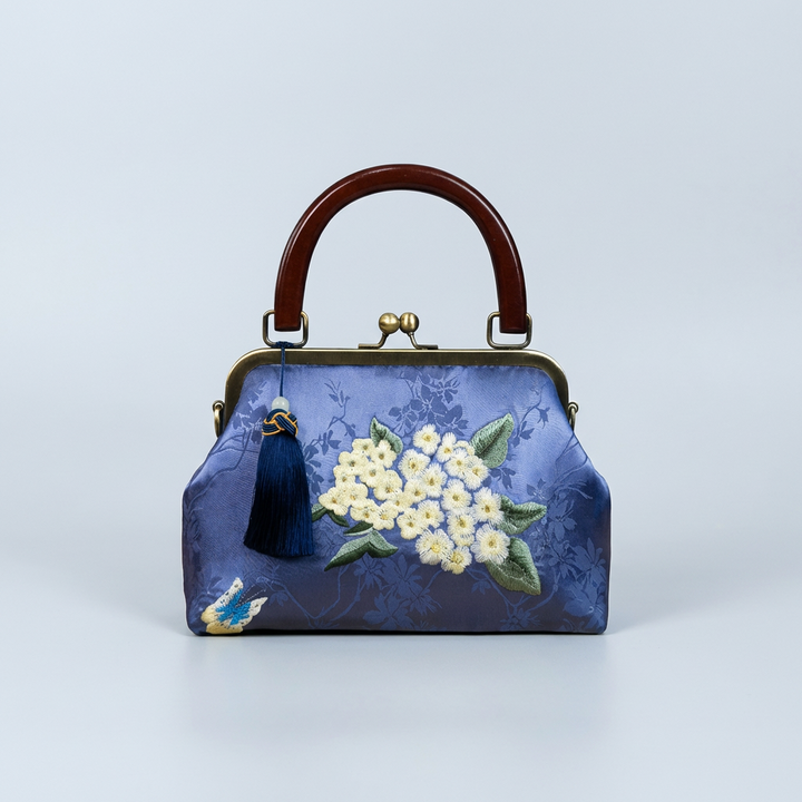 Vibrant royal blue silk evening bag with delicate floral embroidery and a sturdy dark wood handle.