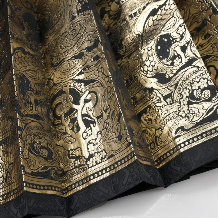 Close-up of the shimmering gold thread dragon embroidery texture on the pleated wrap-around maxi skirt.