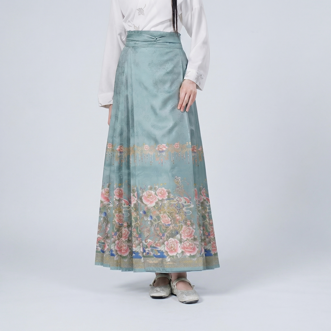 Detailed view of the pleated maxi skirt highlighting the soft teal-blue fabric and intricate vintage-inspired botanical floral patterns.
