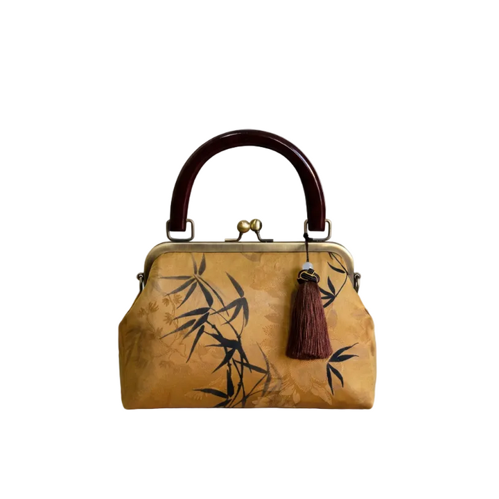 Detailed view of the bright yellow silk handbag with artistic bamboo print and sturdy brown top handle.